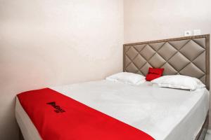 a bed with a red blanket on top of it at RedDoorz near Taman Bekapai 3 Balikpapan in Klandasan Kecil