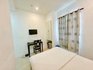 a bedroom with a bed and a desk with a television at Khách sạn Nam Môn in Can Tho
