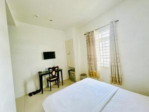 a bedroom with a bed and a desk and a window at Khách sạn Nam Môn in Can Tho