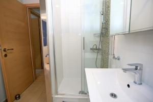 a white bathroom with a shower and a sink at Villa BOSE in Brela