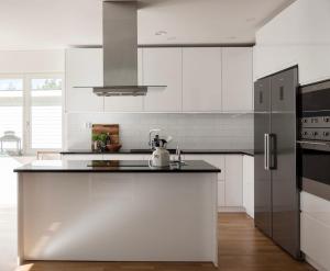 a kitchen with white cabinets and a black refrigerator at BresseInn in Enköping
