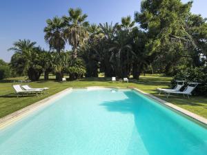 een zwembad met 2 stoelen en palmbomen bij Villa Del Parco in Agnone Bagni