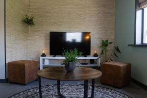 a living room with a television and a table and two stools at B&B Hartenlust kamer de Hooizolder in Bodegraven