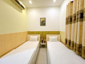 two beds in a small room with curtains at Khách sạn Nam Môn in Can Tho +22 photos