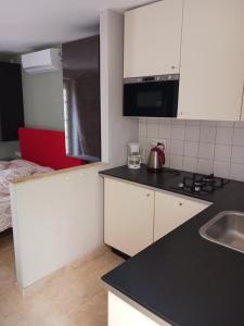 a kitchen with white cabinets and a black counter top at STUDIO chez La Maison Forte in Montaut