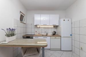 a kitchen with white appliances and a wooden table at Apartman Angelina in Supetar