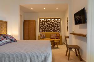 a bedroom with a bed and a chair and a couch at Arancia Elegant Rooms and Suites in Tolo