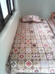 a room with a bed with a quilt on it at Himalayan Mountain Trekkers Hostel in McLeod Ganj