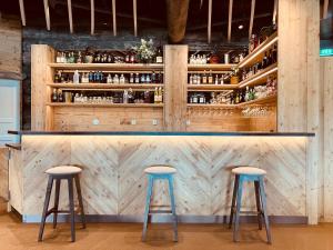 a bar with two stools in front of a wooden wall at HUNURIJÄRVI RESORT***** in Härmä