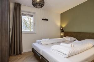 a bedroom with two beds with white sheets and a window at Vakantiepark Leukermeer in Well +88 photos