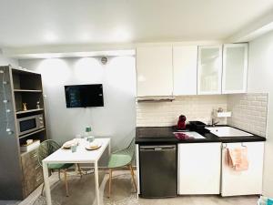 a kitchen with white cabinets and a white table and chairs at Charmant studio Créteil proche Paris, Disneyland, hôpitaux, aéroports in Créteil +5 photos