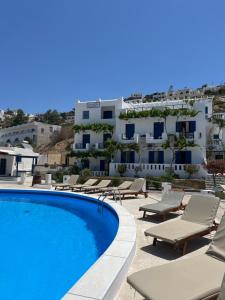 a swimming pool with lounge chairs and a building at Pension Irene in Ios Chora