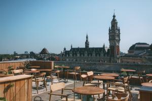 a patio with tables and chairs and a clock tower at Grand Hotel Bellevue - Grand Place in Lille