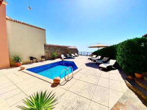 a swimming pool in a patio with chairs and an umbrella at Villa Venus Privacy & Relax in Mošćenička Draga