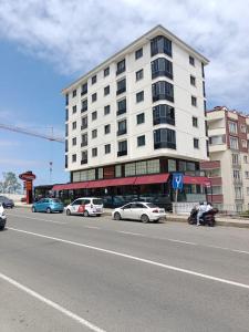 un gran edificio blanco con coches aparcados en el lateral de una calle en White Pearl Residance, en Trabzon