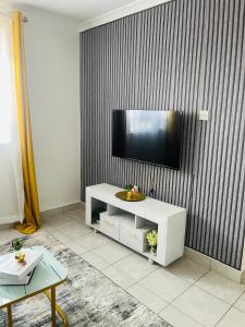a living room with a television on a wall at Bella Homes Thika Town in Thika +2 photos