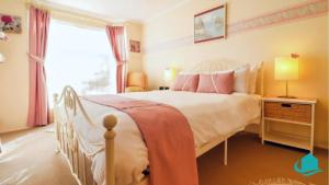 ein Schlafzimmer mit einem weißen Bett mit rosa Kissen in der Unterkunft Bromyard Cottage in Swansea + 12 Fotos