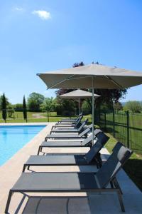 a row of lounge chairs with umbrellas next to a pool at H&ocirc;tel Les Vieilles Tours Rocamadour in Rocamadour