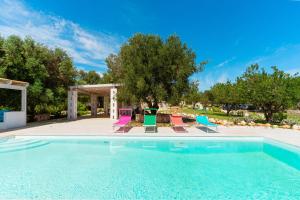 a swimming pool with chairs and a patio at Tenuta di Uma by Perle di Puglia in Carovigno