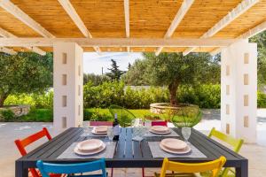 a patio with a black table and colorful chairs at Tenuta di Uma by Perle di Puglia in Carovigno