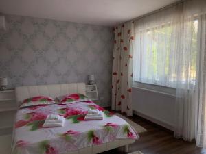 een slaapkamer met een wit bed met roze bloemen erop bij REDhouse in Baia Mare +11 foto's
