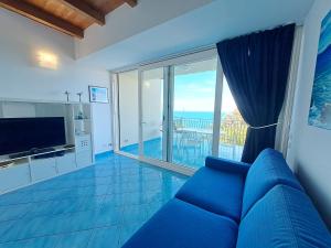 a living room with a blue couch and a large window at Magarà Apartment by Casa in mente in Cefalù