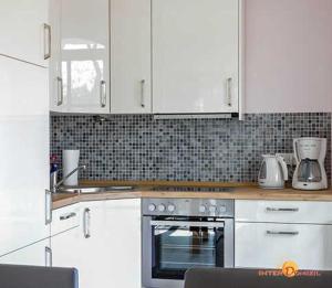 a kitchen with white cabinets and a stove top oven at Haus Meeresblick Ferienwohnung Kra in Baabe