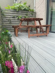a wooden picnic table sitting on a deck with flowers at Five Bedroom Five Bathroom House - Dalkeith in Dalkeith