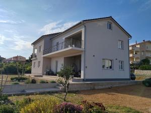 a large white house with a balcony in a yard at Martina in Rab