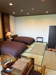 a room with two beds and a table and chairs at Hotel Bokaiso in Takamatsu
