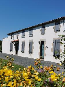 a white building with windows and flowers in the foreground at La Longère de Mina in La Petite-Boissière