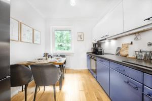Una cocina con gabinetes azules y una mesa con sillas. en FeWo Phönixhütte am Baldeneysee in Kupferdreh, en Essen
