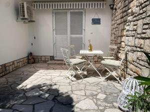 a patio with chairs and a table and a stone wall at Calma bungalows in Portorož