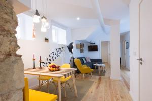 a dining room and living room with a table and yellow chairs at Casa do Castelo 1- Work or Relax in the Historic heart of Lisbon! in Lisbon