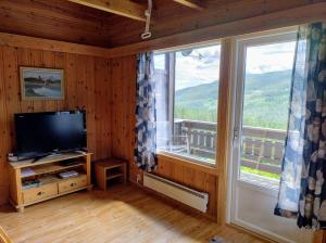 a living room with a television and a large window at Hogstul Hytter - Apartment North in Tuddal