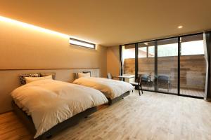 a bedroom with two beds and a desk and a window at Hotel 4CROWNS-ブラックプラン in Katsuyama