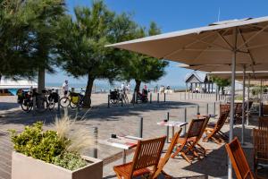un patio con tavoli e ombrelloni sulla spiaggia di Appartement Soulac a Soulac-sur-Mer