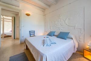 a bedroom with a large white bed with blue pillows at Trullo Contessina in Torre Vado
