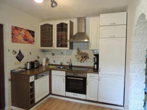 Ferienhaus Weinberg في فيرنيغيروده: مطبخ بخزائن بيضاء وفرن موقد