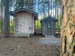 two wooden out houses in a forest with trees at KoloCabins -Huuhanranta 6 in Ruokolahti