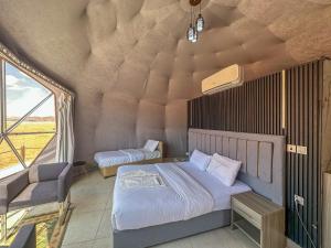a bedroom with two beds in a room with a window at Golde bubble camp in Wadi Rum