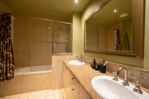ein Badezimmer mit zwei Waschbecken und einer Badewanne und einem Spiegel in der Unterkunft Lily Lakes - Resort Style Living in Cairns + 12 Fotos