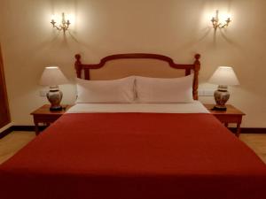a bedroom with a large red bed with two lamps at Samsara in Galle