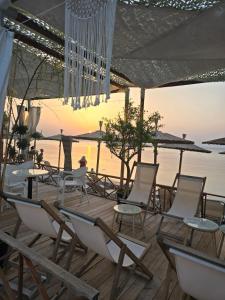 a group of chairs and tables on a deck near the water at Dimi Deluxe in Perea
