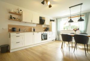 a kitchen with white cabinets and a table and chairs at Ferienwohnung Hyggelig in Waldershof