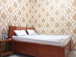 a bedroom with a bed and a wall with wallpaper at Isa Homestay Kudus Mitra Reddoorz in Kudus