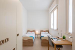 two beds in a room with a desk and a table at La Suite 2 Ondina Viareggio 200m from sea - Happy Rentals in Viareggio