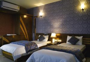 a hotel room with two beds and a wall at Hote Meghnath Palace in Dhupguri