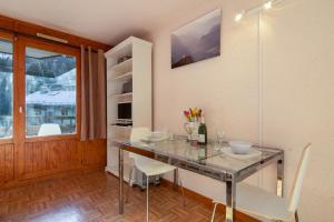 a dining room with a glass table and white chairs at Résidence Le Prarion 24A ski in- ski out - Happy Rentals in Les Houches +16 photos