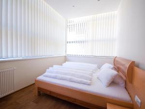 1 cama con sábanas y almohadas blancas en una habitación con ventanas en Apartments Obernosterer, en Kaprun